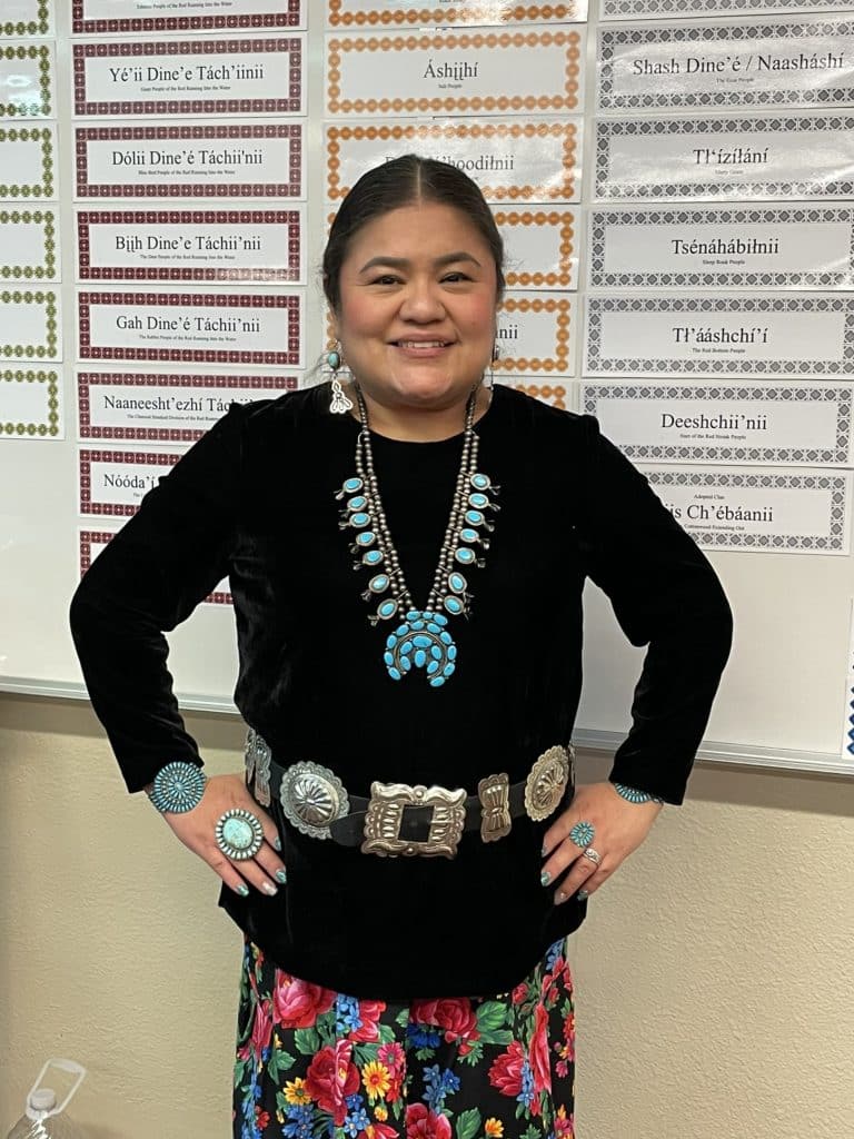 Lavinia Cody, an indigineous woman, wears turquoise jewelry and poses with her hands on hips for a story about indigenous communities and the five year COVID anniversary