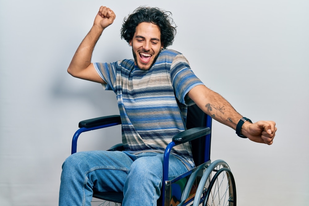 Handsome young Latino man dancing exuberantly in his wheelchair