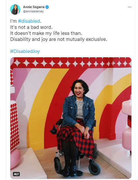 A tweet by Annie Segarra laughing in a jeans jacket and checked skirt, sitting in a wheelchair. The text reads in part: I'm #disabled...Disability and joy are not mutually exclusive."